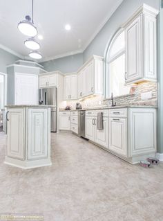 a large kitchen with white cabinets and marble counter tops