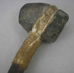 an old rock with a hammer sticking out of it's side on a gray surface