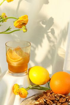 an orange, lemon and pecan drink on a table with flowers in the background