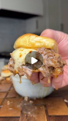 a hand holding a half eaten sandwich on top of a wooden table