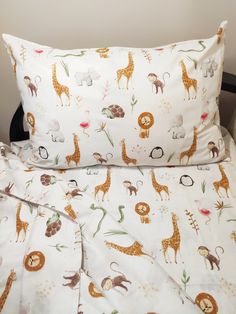 a bed topped with two pillows next to a pillow case covered in animal sheets and blankets