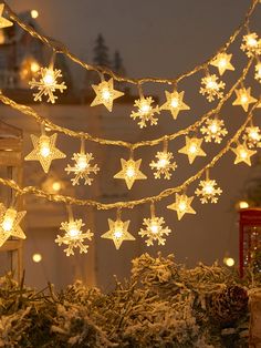 snowflake lights are hanging from a string in front of a christmas tree and other decorations