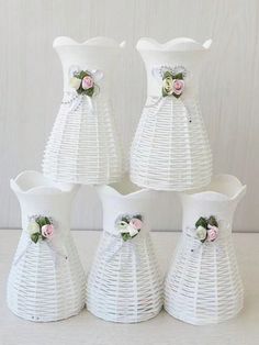 four white vases with flowers and ribbons on them