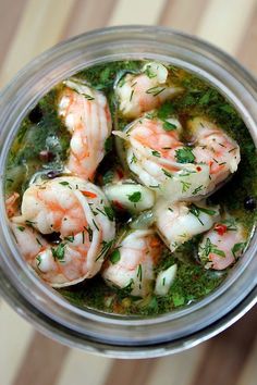 a glass jar filled with shrimp and herbs