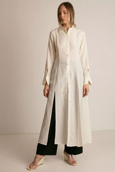 Maxi shirt dress in ivory lyocell poplin. Shirt collar. Front placket with fabric covered buttons. Princess seaming at front and back. Full skirt with front slits at hem. Long sleeves with front facing cuff. Keyhole closure at cuff. Slightly sheer. Ella is 6' tall, 35" bust, 26" waist, 36" hip, and is wearing a size S. Long Shirt Designs For Women, Maxi Sleeves Design, Long Shirt Pattern, Maxi Dresses With Long Sleeves, Dress Shirt And Skirt Outfit, Modest Shirts For Women, Cuff Design Sleeve, Long Shirt Ideas, Long Top With Skirt