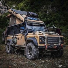 an off - road vehicle parked in the grass with its roof tent on it's back