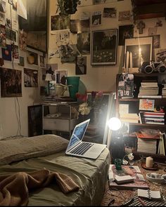 a laptop computer sitting on top of a bed in a room filled with books and pictures