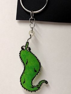 a keychain with a green cartoon character on it's side hanging from a hook