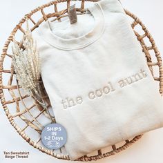 a white shirt that says the cool aunt on it next to a wicker basket