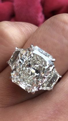 a close up of a person's hand holding a ring with a diamond in it