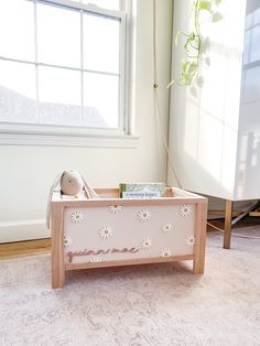 a wooden toy box sitting on the floor next to a window