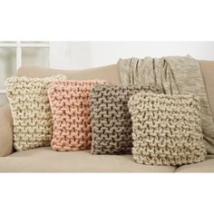 four knitted pillows sitting on top of a couch