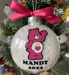 a christmas ornament with a pink teddy bear on it's face and name