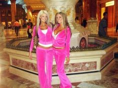 two women in pink outfits standing next to a fountain