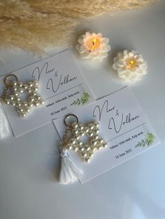 three cards with pearls and tassels on them sitting next to some fake flowers