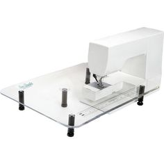 a white sewing machine sitting on top of a glass table next to a computer monitor