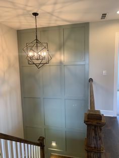 a chandelier hanging from the ceiling in a room with wood floors and white walls