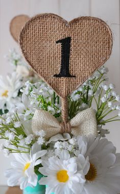 a vase filled with white flowers and a heart shaped number one sign on top of it