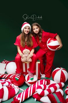 two women in red pajamas and santa hats posing for a photo with christmas decorations on the floor