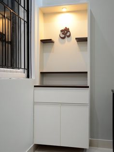 an empty white cabinet with two pairs of shoes on the top shelf in front of it