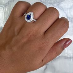 One of a kind pear shaped blue sapphire is surrounded by a double diamond halo - who can say no to that? The perfect pop of color for when you decide to pop the question Great as an engagement ring or anniversary present! Who wouldn't love a diamond halo ring with a blue sapphire center stone? Ever since Princess Di's famous engagement ring, women all over the world have discovered the beauty of blue sapphires. We love this ring especially for sparkling double diamond halo. It's a very special r Pear-shaped Diamond Halo Ring As Gift, Blue Pear-shaped Brilliant Cut Ring, Blue Sapphire Ring With Pear-shaped Center Stone, Blue Pear-shaped Sapphire Ring With Cubic Zirconia, Teardrop Blue Sapphire Ring With Diamond, Blue Pear-shaped Sapphire Ring With Center Stone, Teardrop Sapphire Ring With Diamond, Pear-shaped Halo Ring For Promise, Pear-shaped Halo Ring Gift