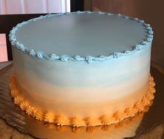 a blue and white frosted cake sitting on top of a wooden table