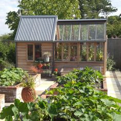 a small wooden house with lots of plants in the yard