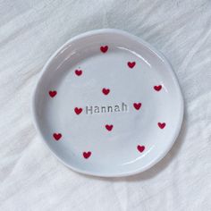 a white plate with red hearts and the word hannah written in small letters on it