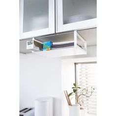 a kitchen with white cupboards and an oven in the corner next to a potted plant