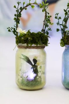 two jars with plants in them sitting on a table