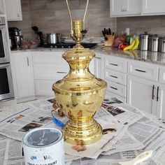 a golden lamp sitting on top of a kitchen counter next to a can of paint