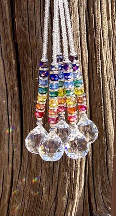 a bunch of glass beads hanging from a wooden pole in front of a tree trunk