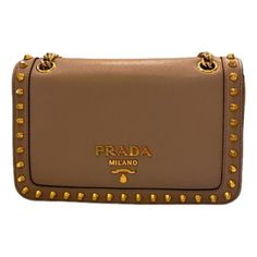 This Cammeo beige calfskin leather is appropriate for any season, adorned with stud accents in a gold finish. The magnetic snap closure opens to a black jacquard lined interior with a zipper and patch pocket. The chain and beige leather strap can be doubled and worn on the shoulder or as a crossbody. This show stopping Prada crossbody bag is sure to highlight any ensemble!    Model: 1BD147  Beige calf-skin leather  Gold-tone hardware  Stud accents  Magnetic closure  Interior black jacquard linin Luxury Brown Shoulder Bag With Metal Logo, Luxury Brown Bag With Metal Logo, Elegant Brown Shoulder Bag With Metal Logo, Chic Brown Bags With Metal Logo, Luxury Studded Shoulder Bag, Elegant Leather Bag With Studs, Elegant Studded Leather Bags, Formal Leather Bags With Studs, Designer Formal Bags With Studs