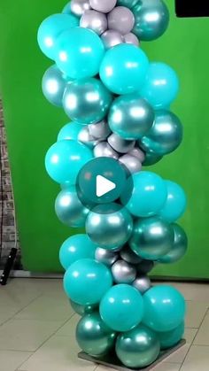 blue and silver balloons are stacked on top of each other in front of a green wall