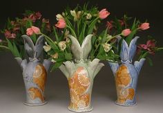 three vases with flowers in them sitting next to each other