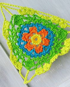 a crocheted doily with an orange, yellow and blue flower on it