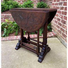 an ornately carved wooden stand on the sidewalk in front of a brick wall and shrubbery