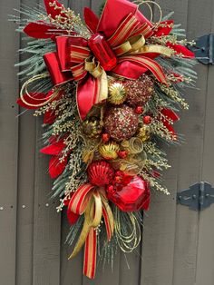 a red and gold christmas wreath hanging on the side of a wooden door with decorations