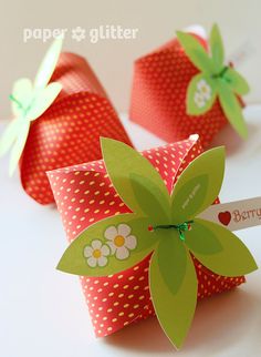 two pink and green paper flowers on top of each other with a name tag attached to them