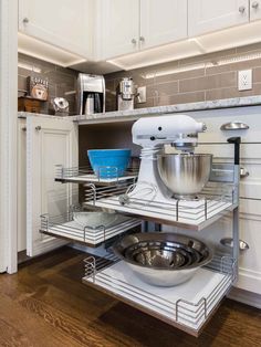 a kitchen with white cabinets and stainless steel appliances in the corner cabinet space, including an open shelf for mixing bowls