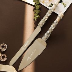 two wedding cake knifes on top of a table next to a pair of scissors