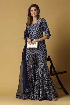 Deep blue short kurta with floral woven pattern on brocade and lace detailing. Paired with flared sharara and dupatta.
Components: 3
Pattern: Woven
Type Of Work: Floral
Neckline: V neck
Sleeve Type: Three quarter
Fabric: Silk and Brocade Blend
Color: Blue
Other Details: 
Side slits
Attached lining
Note: The bag held by the model is not for sale
Occasion: Puja - Aza Fashions Blue Designer Palazzo Set With Self Design, Blue Self Design Palazzo Set For Navratri, Blue Self Design Palazzo Set For Diwali, Bollywood Style Blue Palazzo Set With Self Design, Blue Self-design Palazzo Set For Navratri, Designer Blue Self-design Palazzo Set, Fitted Blue Sharara For Eid, Festive Blue Self-design Palazzo Set, Blue Georgette Sets With Unique Design