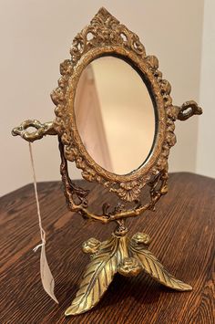 an ornate gold mirror sitting on top of a wooden table next to a toothbrush