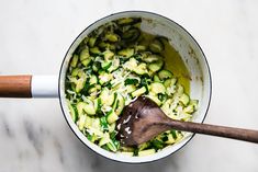 a wooden spoon in a pot filled with zucchini noodles and spinach sauce