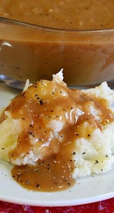 a plate with mashed potatoes covered in gravy next to a casserole dish