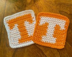 two orange and white crocheted coasters sitting on top of a wooden table