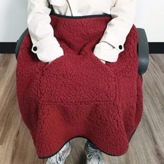 a person sitting in a chair with a red blanket on their lap and feet up