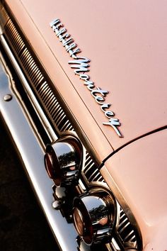 the front end of an old pink car with chrome lettering on it's grille