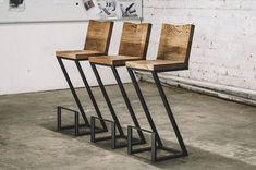 three wooden chairs sitting next to each other on top of metal legs in an empty room