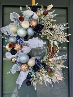 a wreath with ornaments hanging from it's side on the front door to welcome guests